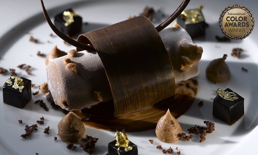 Vanilla ice cream coated in chocolate surrounded by coffee cubes and hazelnuts 
